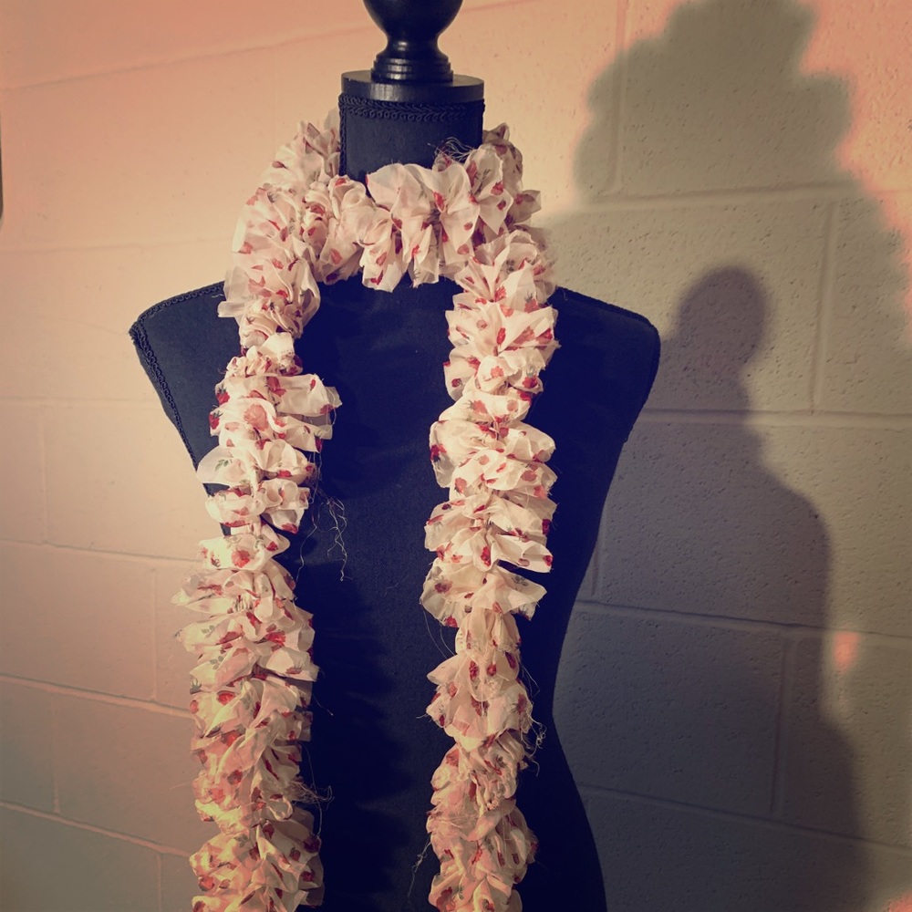 A charming pink scarf with red flowers on it.